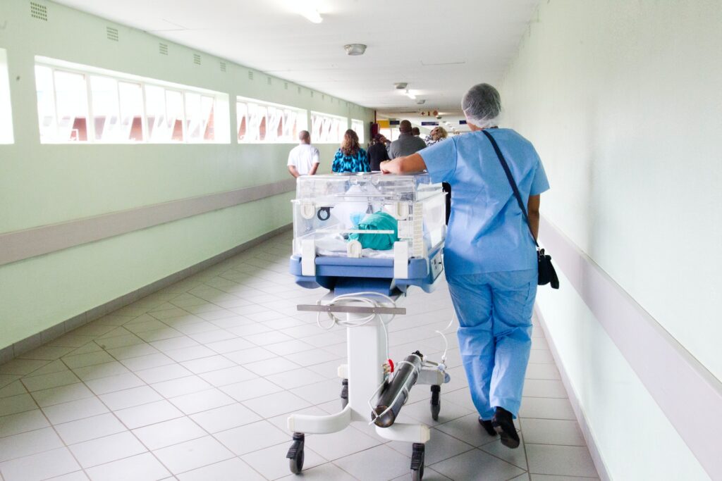 NICU nurse pushing an incubator down a corridor