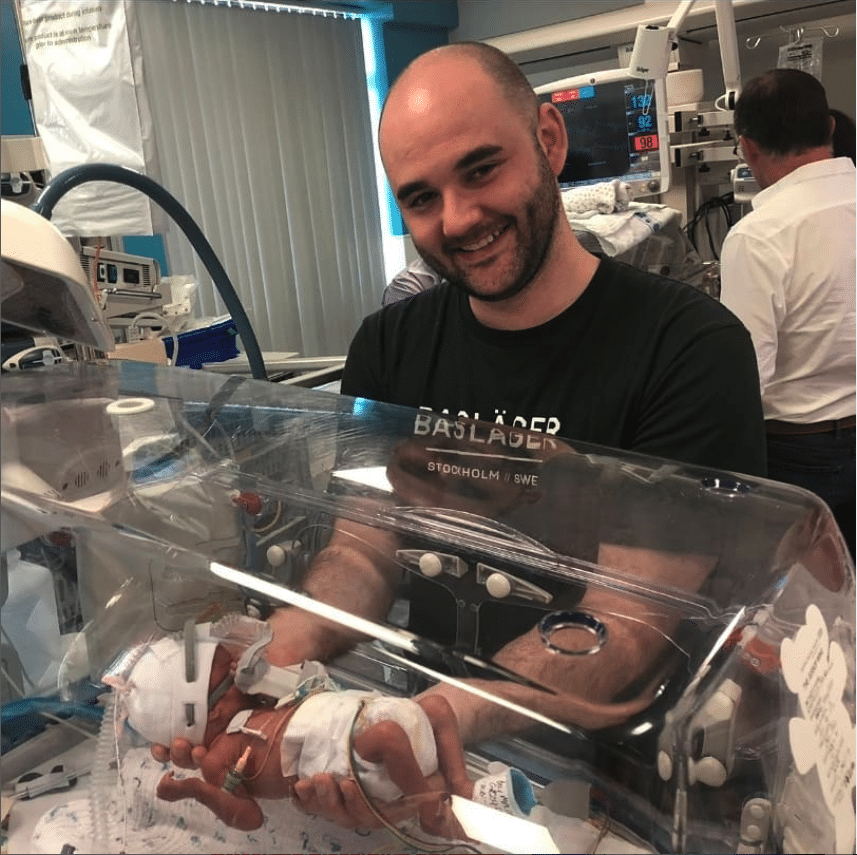 Carl MacDonald holding premature baby son.