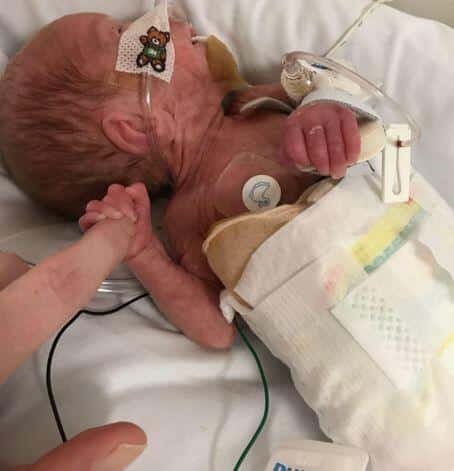 Premature baby Theo holding his mum Rachae's finger